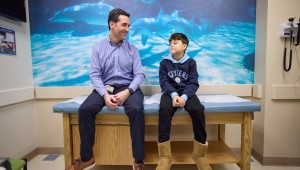 Clinician sitting with young patient in Patient Room