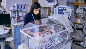 Clinicians in NICU w/ infant patient in incubator