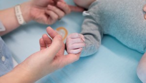 hands grapsing infant laying in bed