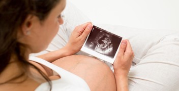 Pregnant woman sitting down looking at an ultrasound photo