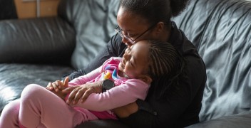Mother and Daughter embracing on couch, smiling