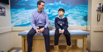 Clinician sitting with young patient in Patient Room