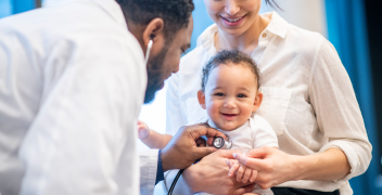 Clinician uses stethoscope to check infant