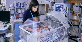 Clinicians in NICU w/ infant patient in incubator