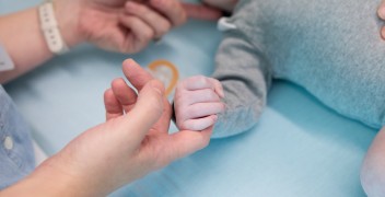 hands grapsing infant laying in bed