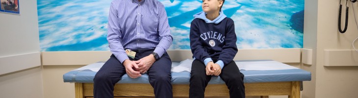 Clinician sitting with young patient in Patient Room