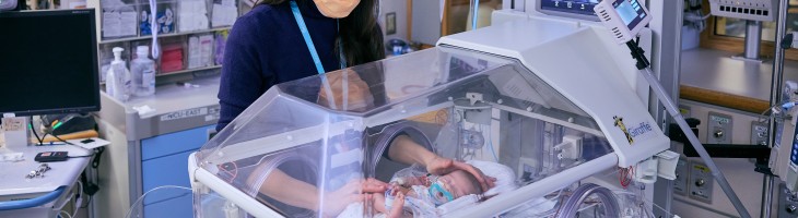 Clinicians in NICU w/ infant patient in incubator