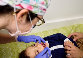 Child receiving dental varnish at a well-child appointment from their pediatric primary care doctor