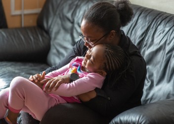 Mother and Daughter embracing on couch, smiling