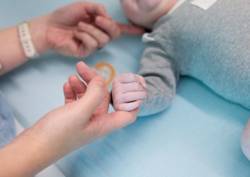 hands grapsing infant laying in bed